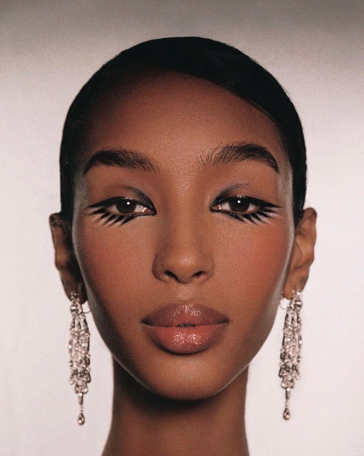A model in a makeup look by Raoúl Alejandre featuring black eyeliner on both the upper and lower lid...