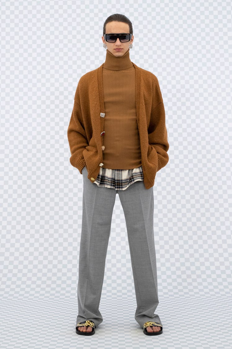 A model in a brown turtleneck and sweater and grey pants at Men’s Fashion Week Spring 2022