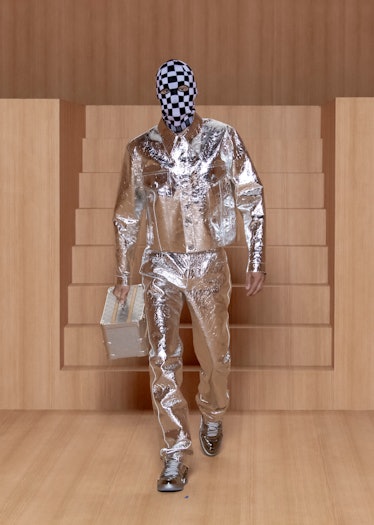 A model wearing a Louis Vuitton men's spring 2022 metallic suit and checkered face covering