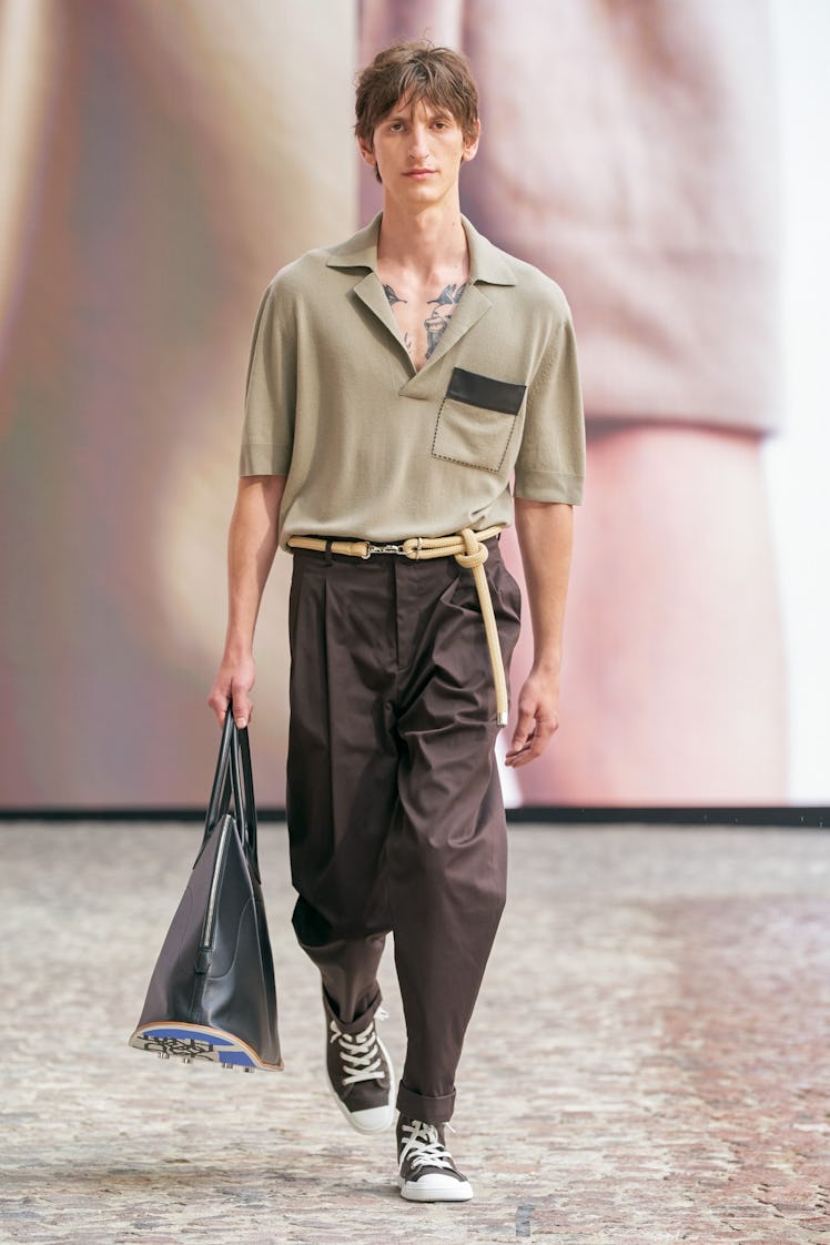 A model in a beige polo shirt and grey trousers by Hermes at Men’s Fashion Week Spring 2022