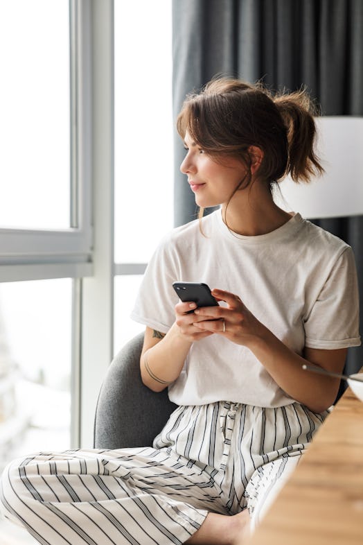 Woman looking out window feeling antisocial due to anxiety from post-pandemic life.