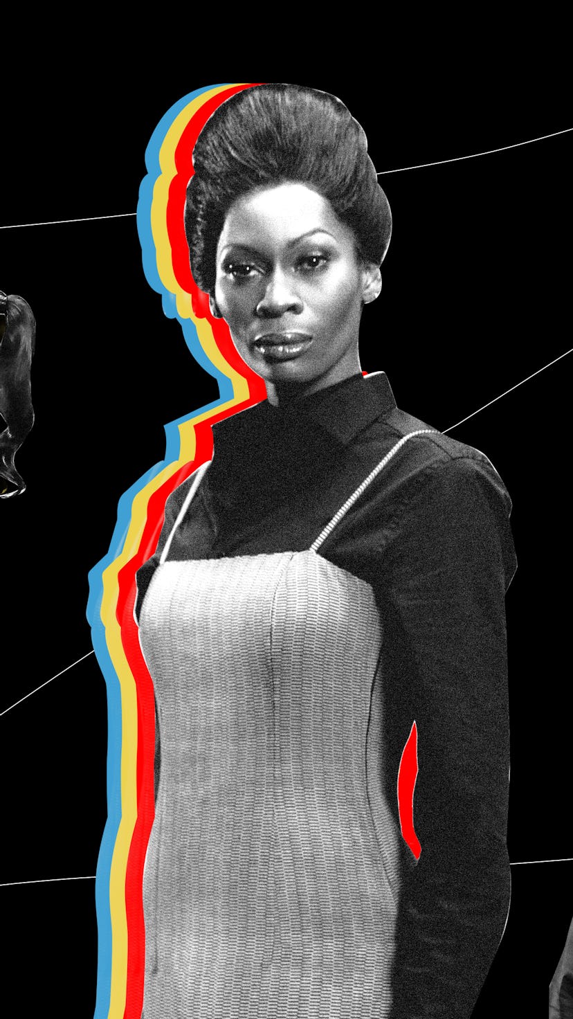 Dominque Jackson in a black dress shirt with a dress over top, looking directly at the camera