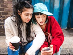A pair of roommates on a stoop, texting using a funny group chat name.
