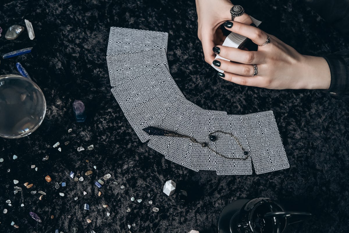 Young woman laying out a tarot card deck, trying to find the one that represents her, per her zodiac sign.