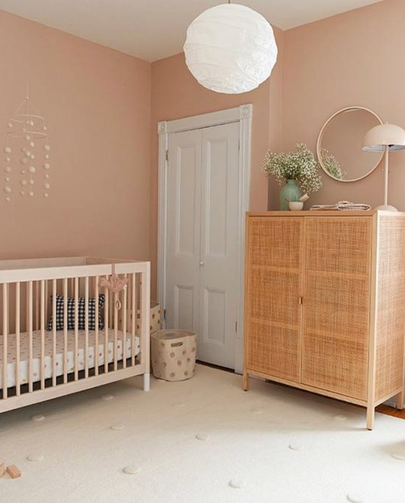 baby nursery with blush walls and cane and wooded accents