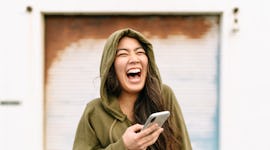 Young woman reading a funny text from her best friend.