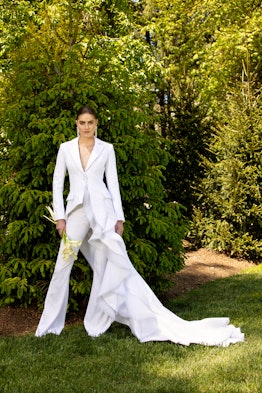 A woman posing in a white Christian Siriano bridal suit