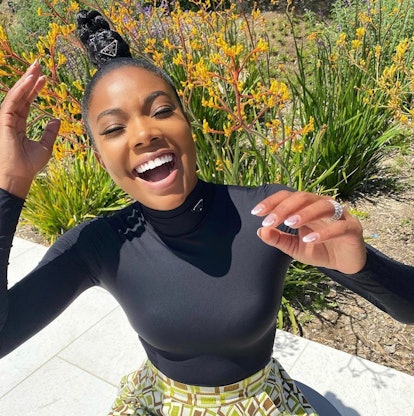 Gabrielle Union laughing outside with white cloud French manicure