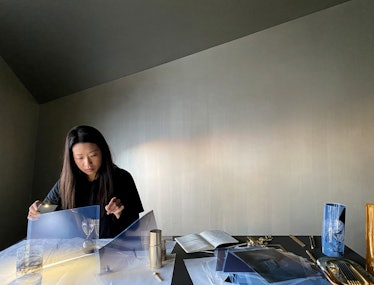 Artist Carla Chan in he studio, sitting and working on one of her installations