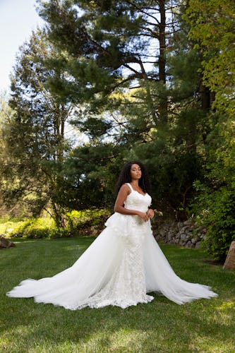 A young bride posing on grass in a wedding dress by Christian Siriano