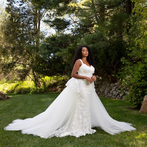 A young bride posing on grass in a wedding dress by Christian Siriano