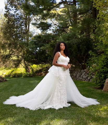 A young bride posing on grass in a wedding dress by Christian Siriano