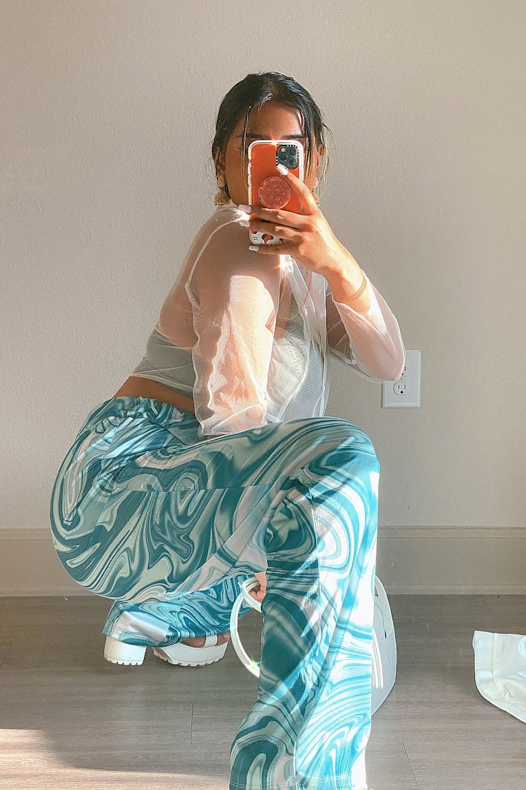 Girl crouching and photographing herself in trendy blue and white party pants 