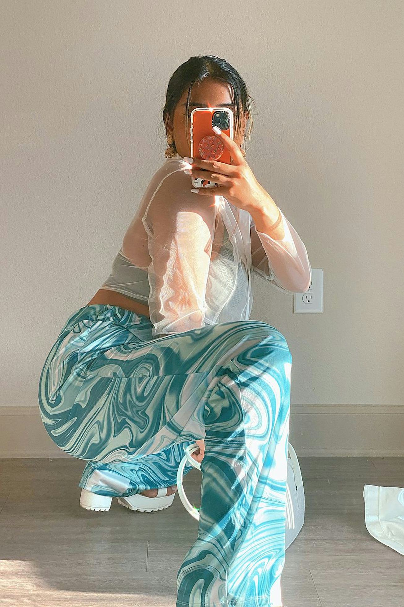 Girl crouching and photographing herself in trendy blue and white party pants