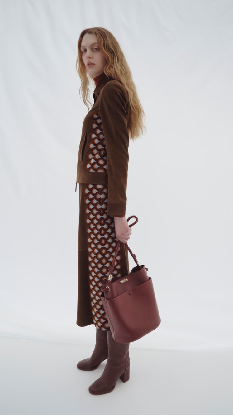 A model posing while wearing a brown Chloé dress and while holding a brown bag