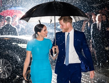 Prince Harry and Meghan Markle in the rain with umbrella.