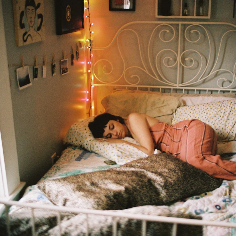 Young woman laying in bed, having vivid dreams during moon transit via specific zodiac sign.