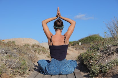Young woman stretching her back — her zodiac sign body part — by meditating.