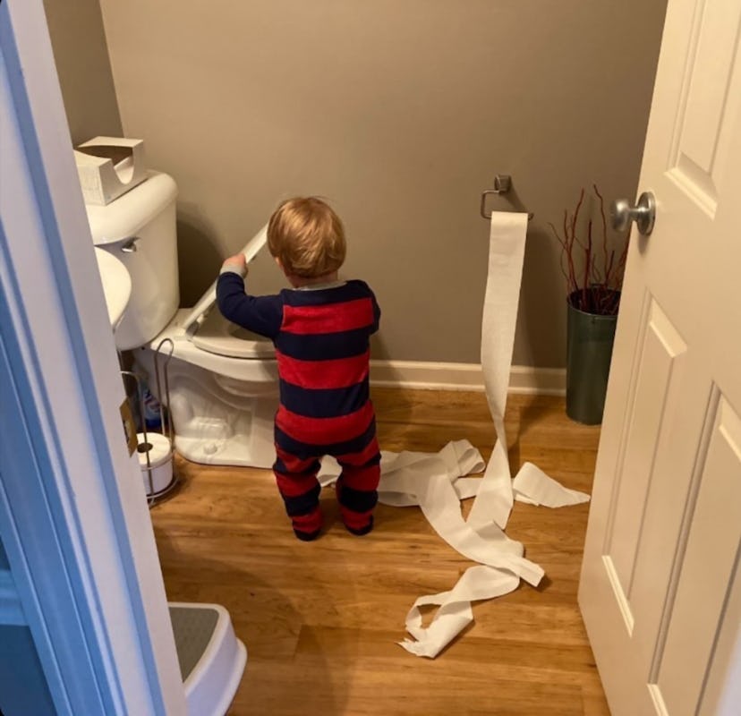 toddler playing with toilet paper in bathroom