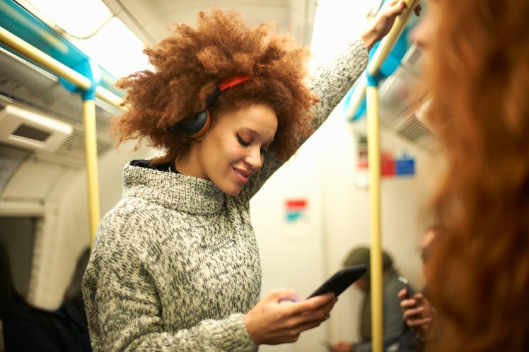 Young woman on the subway, texting her friends with a funny group chat name.