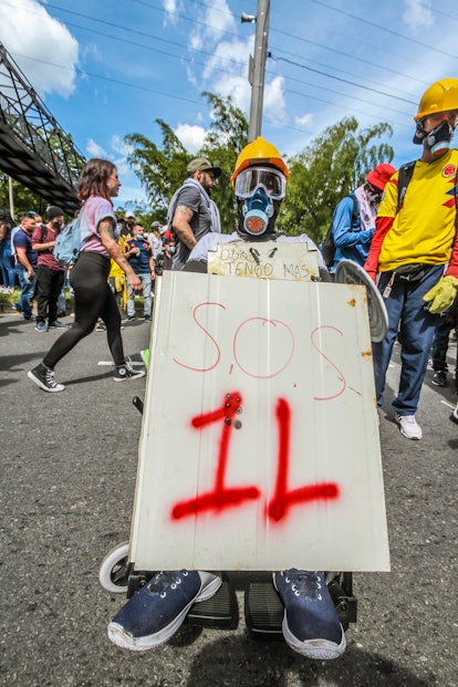 A man protesting with a gas mask and a banner with "SOS 1L" text