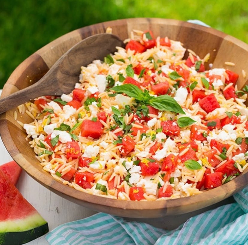 Wooden bowl of watermelon feta orzo salad on table
