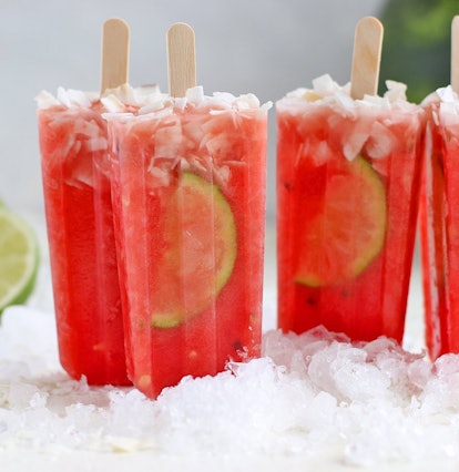 Red popsicles with lime slices sitting upside down on ice