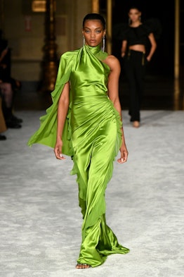 Model walking down the runway in a silk green dress