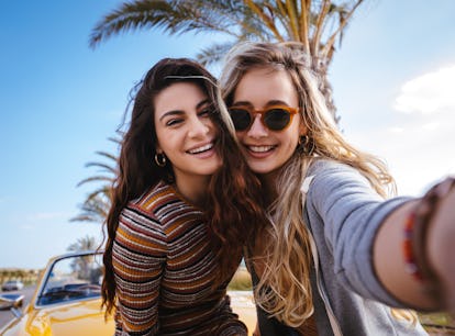 2 cousins smiling while taking a selfie before posting a picture on Instagram with cousin quotes.