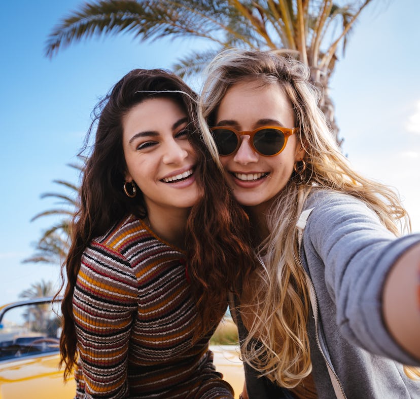 2 cousins smiling while taking a selfie before posting a picture on Instagram with cousin quotes.