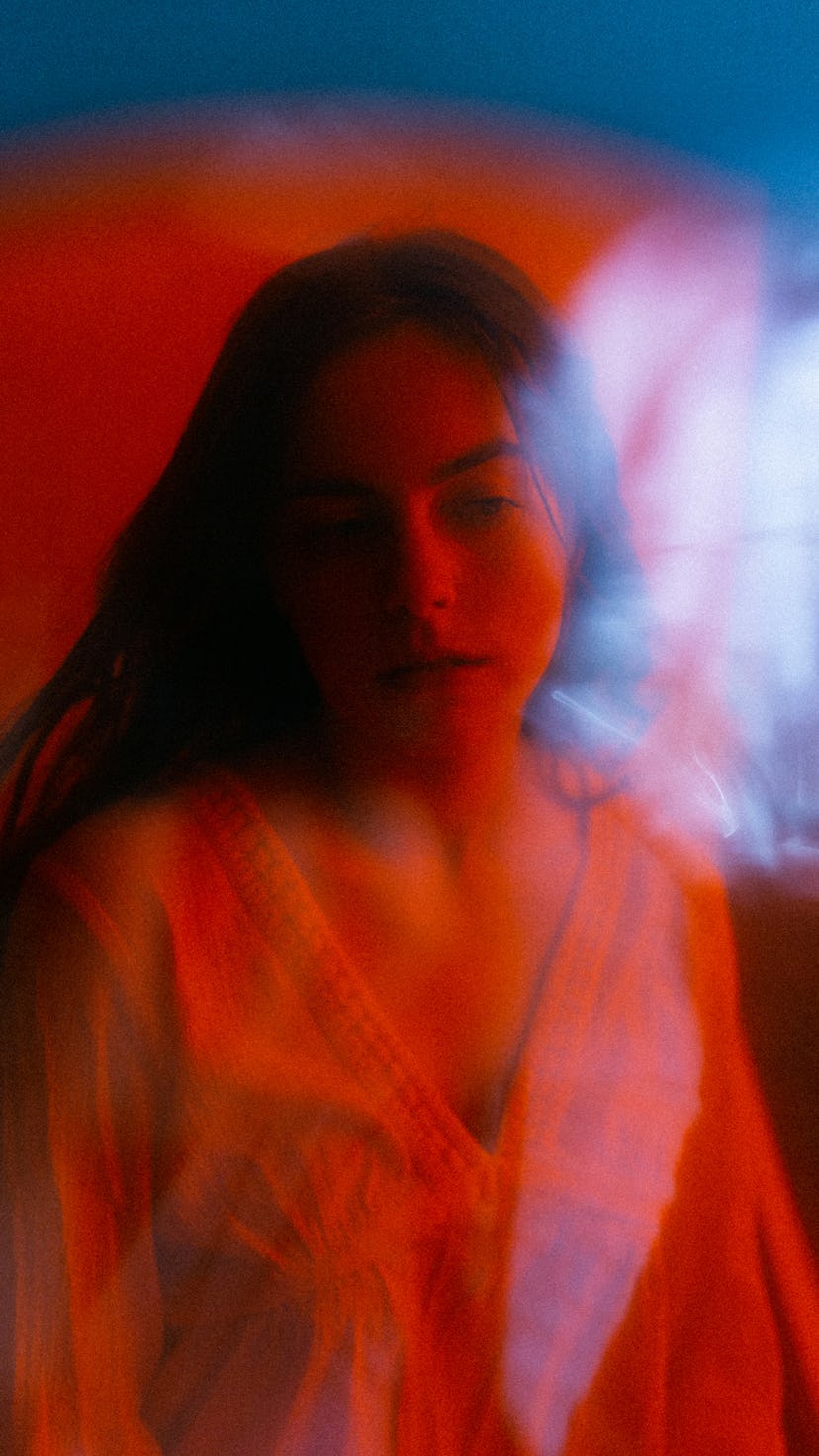 Young woman in red lighting wondering how the July 2021 new moon will affect her zodiac sign, per he...