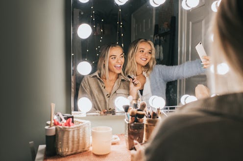 Two women applying make up.