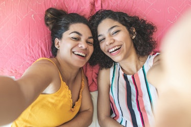 2 cousins taking a smiling selfie on a bed before posting a pic on Instagram with a cousin quote.