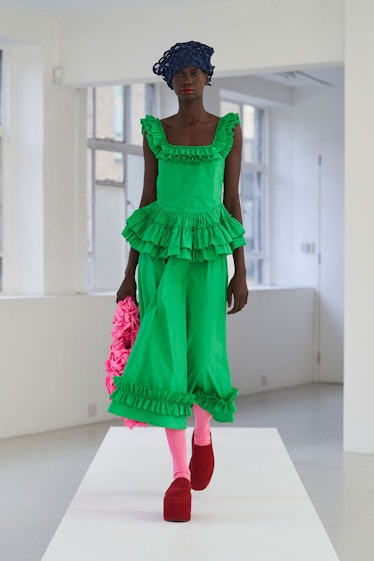 Model wearing a green dress with pink socks and a pink bag by Molly Goddard