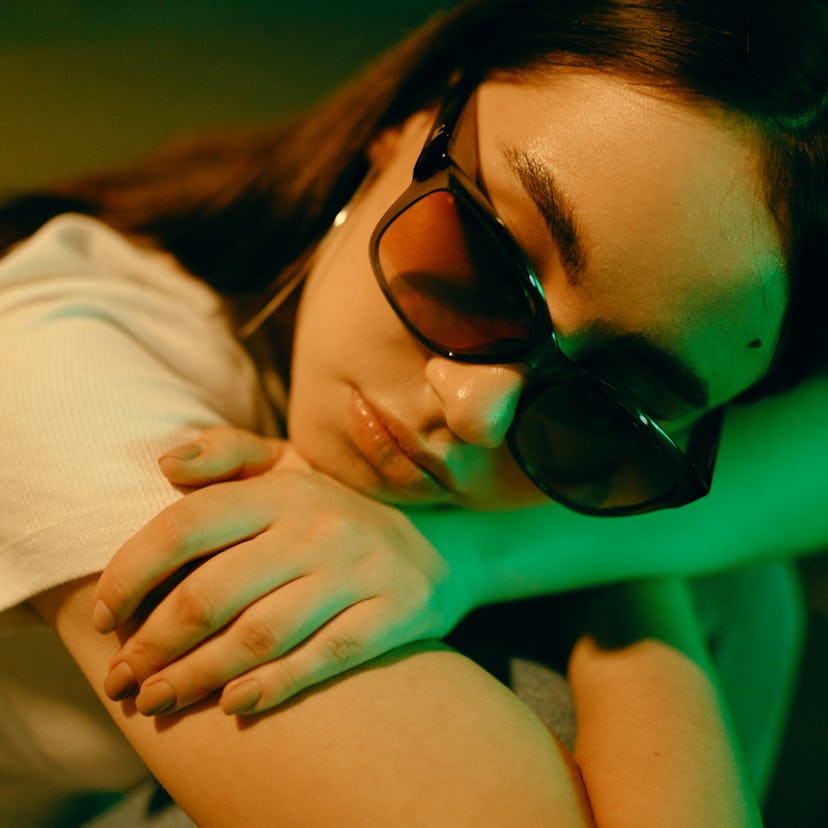 Sad young woman wearing sunglasses with her head on her arms, showing zodiac signs when sad, why are...
