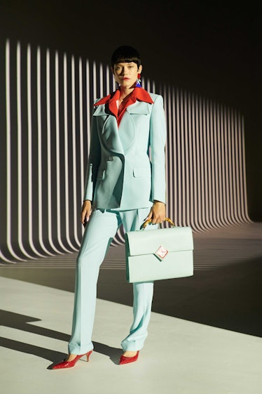 A female model posing while wearing a light blue blazer, a red shirt, and light blue pants
