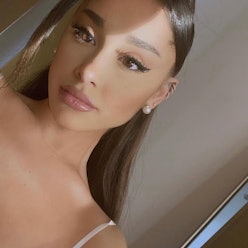 Ariana grande taking a selfie while wearing a white strapped top