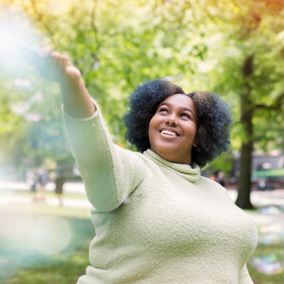 Young woman playing with bubbles to show off her optimistic rising sign meaning.