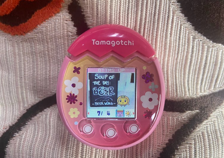 A Tamagotchi character is shown standing next to a sign that reads: Soup of the day, beer