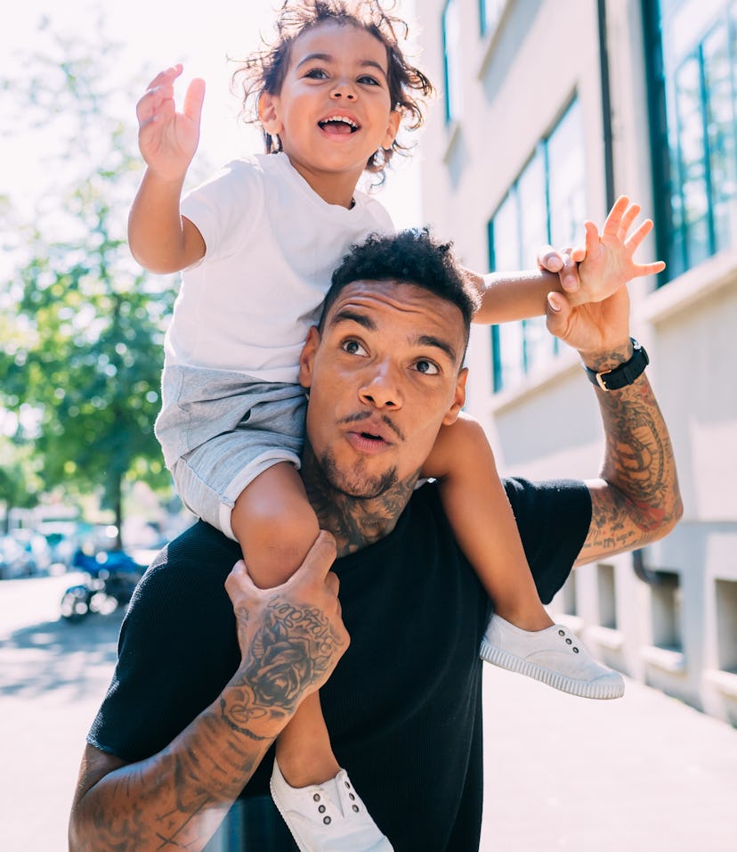 Man with tattoos, carrying toddler on his shoulders