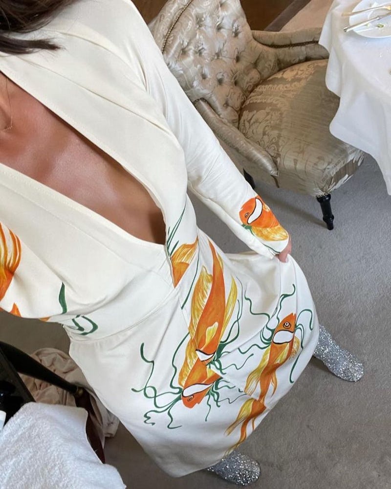 Victoria Beckham wears a white dress in an orange koi fish print.