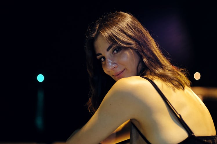 Young woman looking over her shoulder to show her shy rising sign meaning.