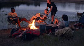 Young friends sitting around a bonfire at a campsite in need of Instagram captions.