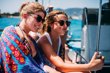 2 young women taking a selfie on a boat before posting on Instagram with a boating caption.