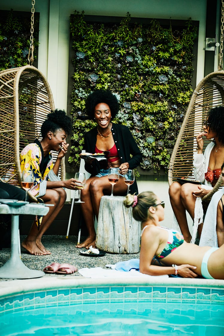 4 young friends at a hotel pool, getting ready to post a pic on Instagram with a resort caption.