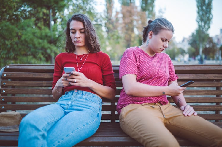 Young women sitting on a bench passive-aggressively fighting via text to show how their zodiac signs...