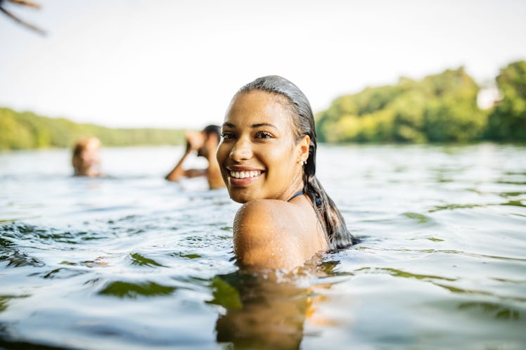 Young woman swimming in a lake with her friends in need of lake captions for Instagram.