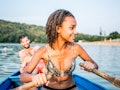 Young woman paddling a boat out on a lake with her boyfriend before posting on Instagram with a lake...