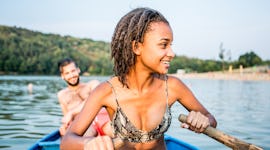 Young woman paddling a boat out on a lake with her boyfriend before posting on Instagram with a lake...