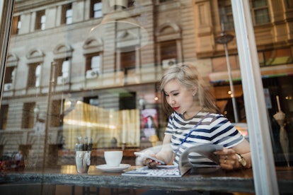 Young woman at a coffee shop writing down a plan to ask for her next raise in her diary.